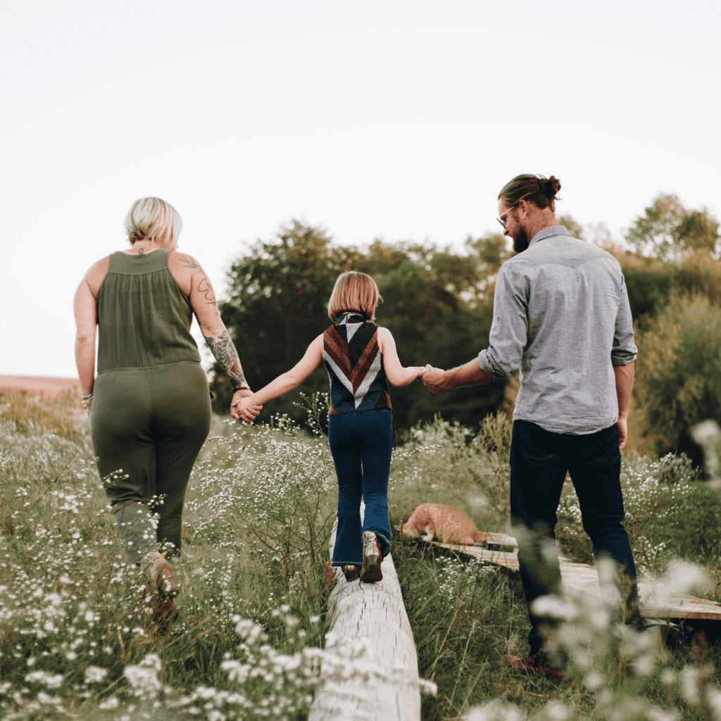 Grunden Finncial Advisory, based in the heart of Denton, TX. Parents walking alongside child balancing on felled tree trunk.